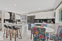 Kitchen featuring white cabinetry, black subway tile backsplash, and stainless steel appliances - 