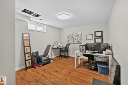 Spacious room featuring wood-finish flooring, light gray walls, and a contemporary flush-mount ceiling light - 