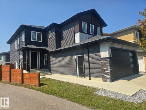 Contemporary multi-level residence featuring dark siding, a covered entry, and a two-car garage with modern window panels - 228 36 Street Sw, Edmonton, AB - Outdoor
