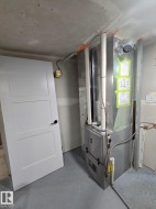 Modern HVAC system with exposed ductwork, concrete flooring, and a white three-panel door - 