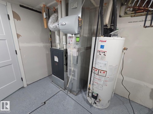 Utility space featuring a water heater, furnace, and a light gray epoxy floor - 228 36 Street Sw, Edmonton, AB - Indoor Photo Showing Basement