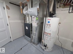 Utility space featuring a water heater, furnace, and a light gray epoxy floor - 