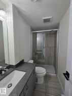 Full bathroom with a walk-in shower featuring a glass enclosure and wood-finish tile surround - 
