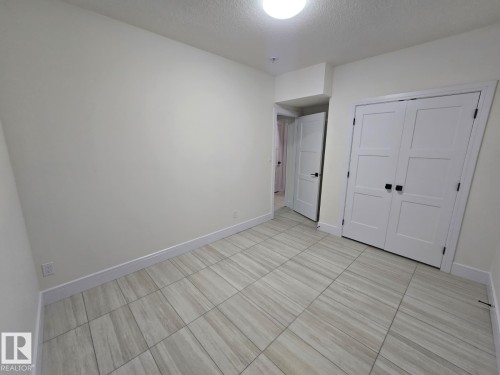 Room featuring light-colored walls and wood-finish tile flooring - 228 36 Street Sw, Edmonton, AB - Indoor Photo Showing Other Room