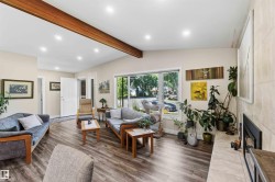 Spacious living area featuring wood-finish flooring, recessed lighting, and a prominent exposed beam - 