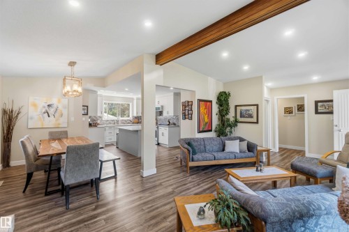 Expansive open-concept interior featuring wood-finish flooring throughout, recessed lighting, and a prominent exposed beam - 11351 35A Avenue Nw, Edmonton, AB - Indoor