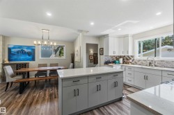 Expansive open-concept kitchen and dining area featuring wood-finish flooring - 