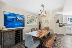 Dining area featuring wood-finish flooring, a contemporary chandelier, and a large window - 
