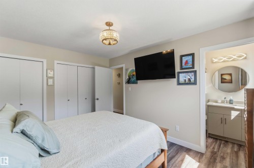 Room featuring wood-finish flooring, a decorative chandelier, and two sets of bi-fold closets - 11351 35A Avenue Nw, Edmonton, AB - Indoor Photo Showing Bedroom