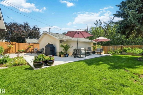 Spacious backyard featuring a large concrete patio, expansive lawn area, and a wood privacy fence - 11351 35A Avenue Nw, Edmonton, AB - Outdoor With Deck Patio Veranda