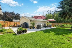 Spacious backyard featuring a large concrete patio, expansive lawn area, and a wood privacy fence - 