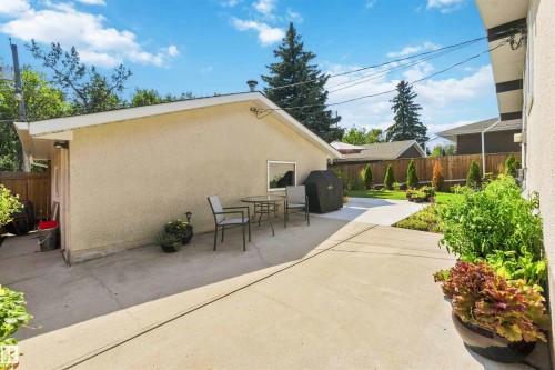 Expansive concrete patio area with a stucco-finished garage structure featuring a small window - 11351 35A Avenue Nw, Edmonton, AB - Outdoor