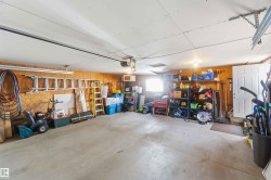 Spacious garage featuring a concrete floor, plywood walls, and overhead lighting - 