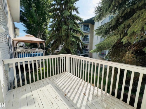 Expansive outdoor deck with white railing, overlooking mature trees and greenery - #48 6608 158 Av Nw, Edmonton, AB - Outdoor With Exterior