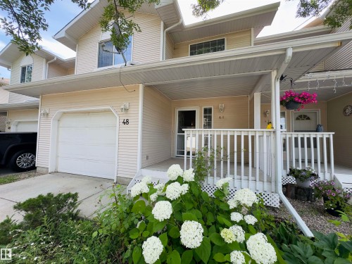 Exterior featuring a covered porch, white railing, and a single-car garage - #48 6608 158 Av Nw, Edmonton, AB - Outdoor With Facade