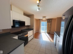 Kitchen featuring white cabinetry, dark speckled countertops, and an integrated black range with an overhead microwave - 