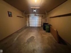 Single-car garage featuring a sectional overhead door, painted walls, concrete flooring, and an overhead light fixture - 