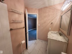 Bathroom featuring a white vanity with a stone countertop, a rectangular mirror, and a decorative light fixture - 