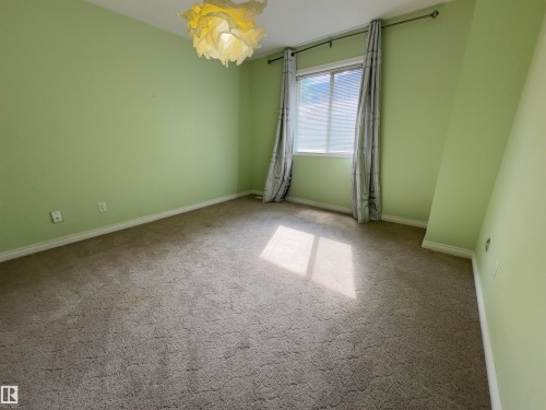 Room featuring a window with vertical blinds, a textile light fixture, and light green painted walls - #48 6608 158 Av Nw, Edmonton, AB - Indoor Photo Showing Other Room