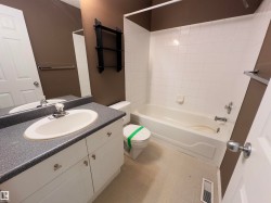 Bathroom featuring a white vanity with an integrated sink, a speckled countertop, and a full-width mirror - 