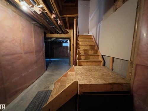 Unfinished basement with exposed wood framing, concrete flooring, and partial insulation - #48 6608 158 Av Nw, Edmonton, AB - Indoor