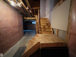 Unfinished basement with exposed wood framing, concrete flooring, and partial insulation - 