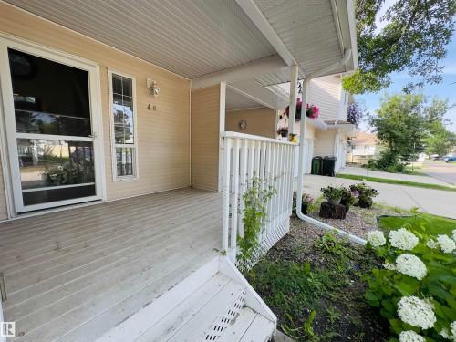 Covered porch entry featuring vinyl siding and a white railing - #48 6608 158 Av Nw, Edmonton, AB - Outdoor With Deck Patio Veranda With Exterior