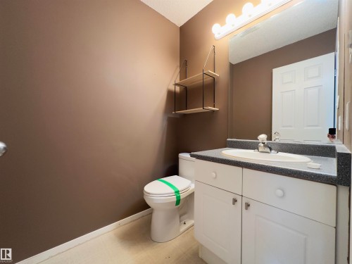 Bathroom featuring a white vanity with an integrated sink, speckled countertop, and white cabinetry - #48 6608 158 Av Nw, Edmonton, AB - Indoor Photo Showing Bathroom
