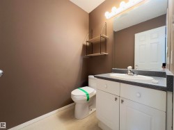 Bathroom featuring a white vanity with an integrated sink, speckled countertop, and white cabinetry - 