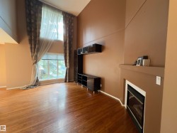 Living room with vaulted ceiling, wood-finish flooring, and expansive windows - 