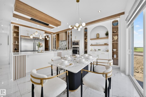Open-concept kitchen and dining area featuring a marble-finish dining table, gold-accented seating, and white cabinetry - 423 Robinson Bv, Leduc, AB - Indoor Photo Showing Dining Room