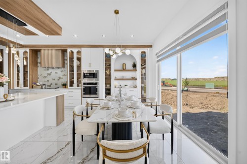 Spacious dining area featuring a long rectangular table, modern chandelier, and large sliding glass doors - 423 Robinson Bv, Leduc, AB - Indoor