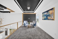 Carpeted upper-level hall featuring a black tray ceiling with recessed lighting and a central chandelier - 