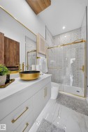 Bathroom featuring a gold vessel sink, white cabinetry with gold hardware, and a walk-in shower with a glass enclosure - 