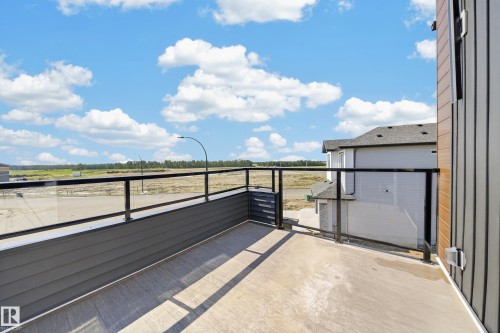 Outdoor balcony featuring glass panel railings, wood-look flooring, and horizontal plank siding - 423 Robinson Bv, Leduc, AB - Outdoor With View