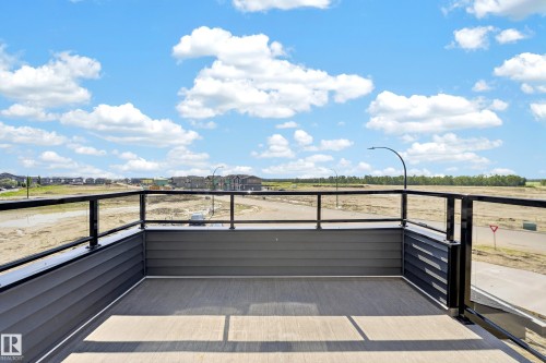 Balcony featuring composite decking, dark gray horizontal siding, and a black metal railing with glass panels - 423 Robinson Bv, Leduc, AB - Outdoor With View