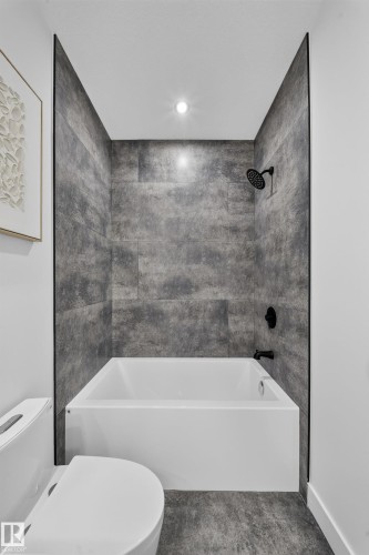 Shower-tub combination featuring large format grey tile surround and matte black fixtures - 423 Robinson Bv, Leduc, AB - Indoor Photo Showing Bathroom