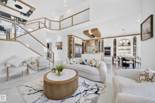 Open-concept living space featuring high ceilings and a grand staircase with glass railings and wood-finish accents - 423 Robinson Bv, Leduc, AB - Indoor Photo Showing Living Room