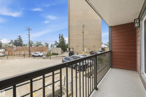 Private balcony featuring composite wood siding, a textured concrete floor, and a black metal railing - #8 10931 83 St Nw, Edmonton, AB - Outdoor With Balcony With Exterior