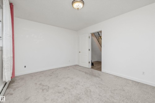 Carpeted room with a ceiling-mounted light fixture, white walls, and white trim - #8 10931 83 St Nw, Edmonton, AB - Indoor Photo Showing Other Room