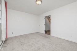 Carpeted room with a ceiling-mounted light fixture, white walls, and white trim - 