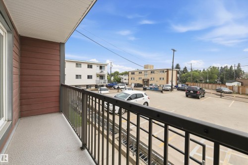 Private balcony with textured flooring, dark metal railings, and horizontal wood-finish siding - #8 10931 83 St Nw, Edmonton, AB - Outdoor With Balcony With Exterior
