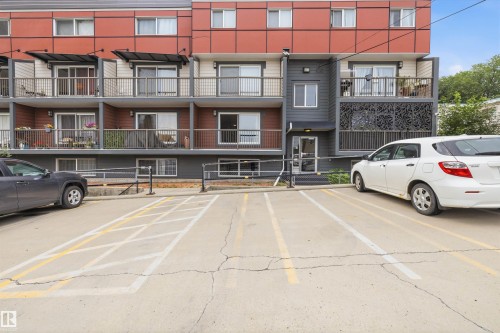 Multi-level residential building featuring private balconies with metal railings, a modern red and gray facade, and ground-level entryways - #8 10931 83 St Nw, Edmonton, AB - Outdoor With Balcony With Facade