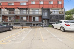 Multi-level residential building featuring private balconies with metal railings, a modern red and gray facade, and ground-level entryways - 