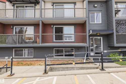 Multi-level building exterior featuring multiple balconies with metal railings, a ground-level entrance with an awning, and a decorative privacy screen - #8 10931 83 St Nw, Edmonton, AB - Outdoor With Balcony With Facade