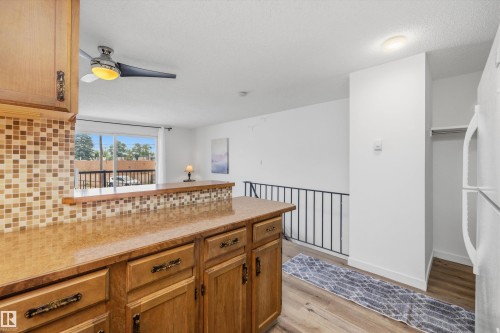 Kitchen featuring wood-finish cabinetry, a textured backsplash, and a breakfast bar counter - #8 10931 83 St Nw, Edmonton, AB - Indoor