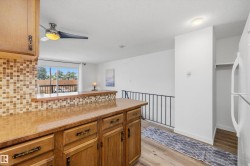 Kitchen featuring wood-finish cabinetry, a textured backsplash, and a breakfast bar counter - 