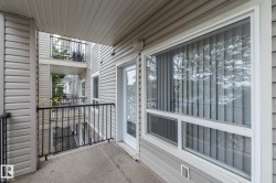 Private balcony featuring concrete flooring, black metal railings, and a white framed glass door - 