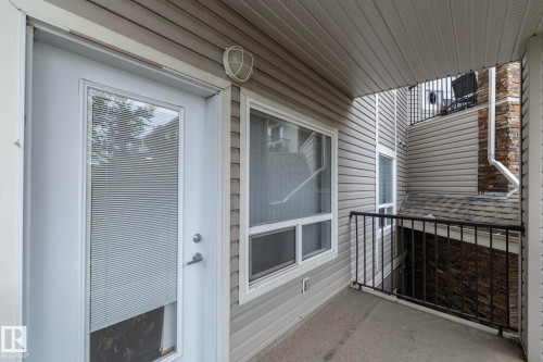 Private balcony featuring a concrete floor, black metal railings, and an exterior door with integrated blinds - #6201 7331 South Terwillegar Dr Nw, Edmonton, AB - Outdoor With Exterior