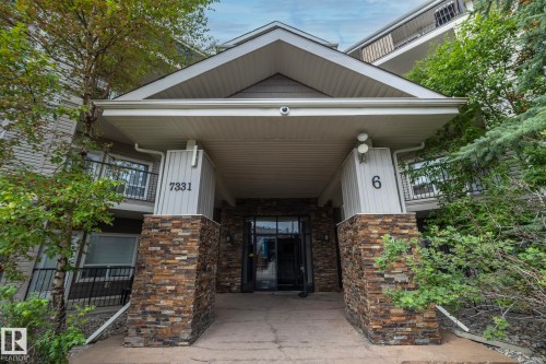 Entryway featuring a covered porch, stone veneer columns, multi-story siding, and an opaque glass double door - #6201 7331 South Terwillegar Dr Nw, Edmonton, AB - Outdoor With Balcony